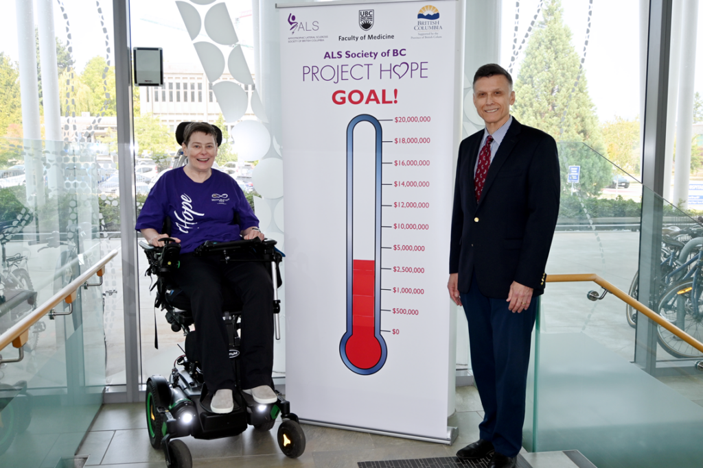 Dr. Erik Pioro stands beside Jan Bruce with the PROJECT HOPE thermometer banner sign between them.